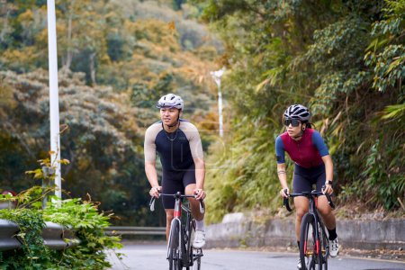 Téléchargez les photos : Jeune asiatique couple cyclistes équitation vélo sur la route rurale - en image libre de droit