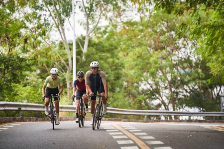 Foto de Grupo de tres jóvenes ciclistas adultos asiáticos montar en bicicleta en carretera rural - Imagen libre de derechos