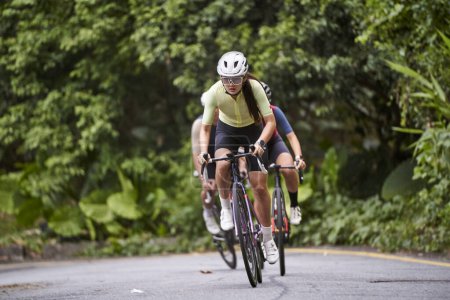 Téléchargez les photos : Groupe de jeunes cyclistes adultes asiatiques à vélo sur la route rurale - en image libre de droit
