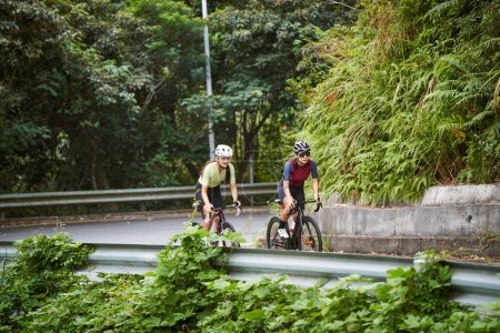 Foto de Dos jóvenes asiáticas ciclistas montar en bicicleta en carretera rural - Imagen libre de derechos