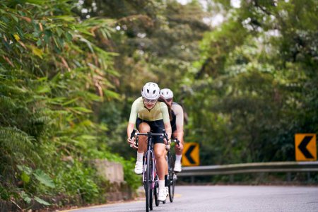Téléchargez les photos : Groupe de jeunes cyclistes professionnels asiatiques équitation vélo formation sur la route rurale - en image libre de droit
