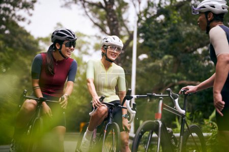 Foto de Grupo de tres feliz joven asiático ciclistas charlando conversando mientras montar en bicicleta al aire libre - Imagen libre de derechos