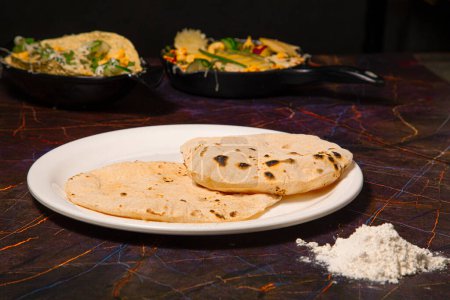 Foto de Cocina tradicional india Chapati o Roti, o Pan indio en plato blanco con harina - Imagen libre de derechos