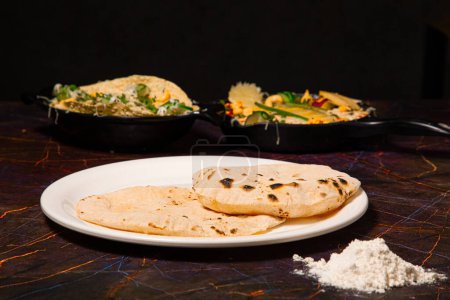 Téléchargez les photos : Cuisine traditionnelle indienne Chapati ou Roti, ou pain indien dans une assiette blanche avec de la farine - en image libre de droit