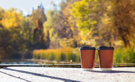 Téléchargez les photos : Deux tasses de café près d'un lac en automne. Scène romantique. Concept esthétique d'automne. - en image libre de droit
