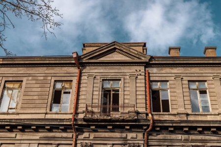 Historische Gebäudefassade mit Außenrohren und zerbrochenen Fensterscheiben in Armenien, Eriwan