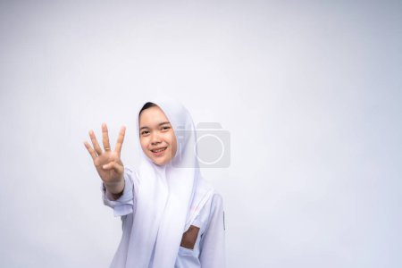 Aufgeregte indonesische Gymnasiastin in weiß-grauer Uniform, die per Handbewegung die Zahl vier gibt