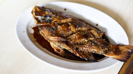 Ikan nila bakar (tilapia a la parrilla). tilapia a la parrilla con salsa de soja dulce y medio cocida