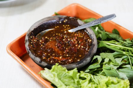 Sambal ulek terasi (rote Chilipaste) serviert auf einem Steingut-Teller. gegessen mit rohem Gemüse oder in Indonesien Lalapan genannt