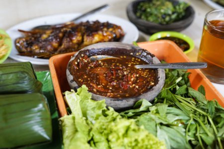 Sambal ulek terasi (rote Chilipaste) serviert auf einem Steingut-Teller. gegessen mit rohem Gemüse oder in Indonesien Lalapan genannt