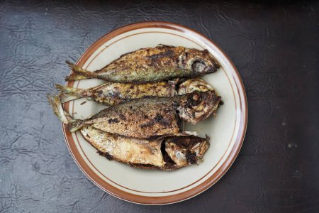 Fried mackerel fish (ikan kembung goreng) isolated on brown background