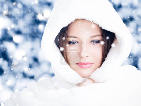 Foto de Felices fiestas, estilo de vida y moda de invierno, hermosa mujer con abrigo de piel esponjosa blanca, nevando nieve en la naturaleza del bosque nevado como Navidad, Año Nuevo y estilo de retrato de vacaciones - Imagen libre de derechos
