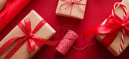 Foto de Preparación de Navidad, día de boxeo y días festivos, regalo, papel artesanal de Navidad y cintas para cajas de regalos sobre fondo rojo como herramientas de envoltura y decoraciones, regalos de bricolaje como diseño de laicos planos de vacaciones - Imagen libre de derechos