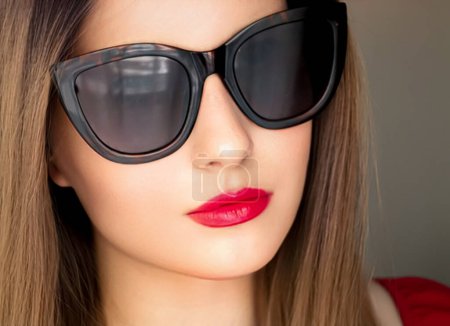 Foto de Belleza, moda y estilo, retrato facial de una mujer hermosa que usa gafas de sol de ojo de gato con estilo y maquillaje de lápiz labial rojo, accesorio de lujo y estilo de vida de verano, glamour y apariencia elegante. - Imagen libre de derechos