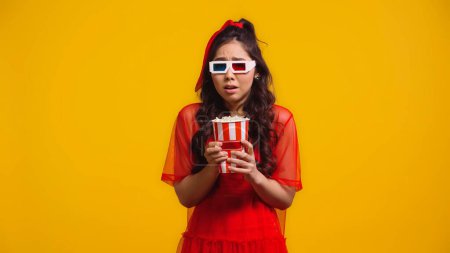 Téléchargez les photos : Effrayé asiatique femme dans 3d lunettes manger pop-corn isolé sur jaune - en image libre de droit