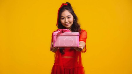 Téléchargez les photos : Joyeuse jeune asiatique femme tenue enveloppé présent isolé sur jaune - en image libre de droit
