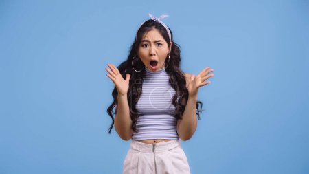 impactado asiático mujer con abierto boca gesto aislado en azul 