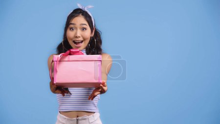 Téléchargez les photos : Excité jeune asiatique femme tenue enveloppé présent isolé sur bleu - en image libre de droit