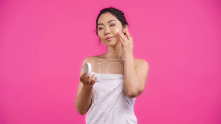 Téléchargez les photos : Asiatique jeune femme dans serviette application visage crème isolé sur rose - en image libre de droit