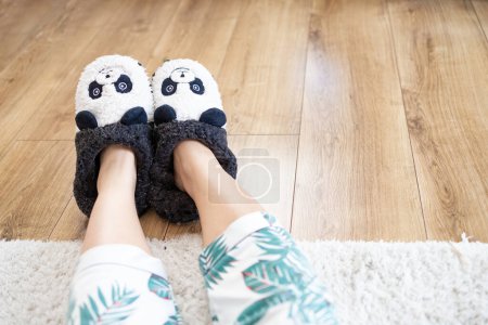 Photo for Young woman in soft funny slippers at home on wooden floor. - Royalty Free Image
