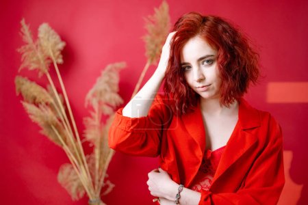 Fashionable young woman in a red suit. Red background.