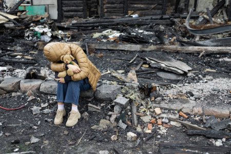 Foto de Una chica al lado de una casa destruida por la guerra. Guerra en Ucrania. Refugiados ucranianos. Niño en las ruinas de su casa destruida por la guerra. Concepto de paz - Imagen libre de derechos