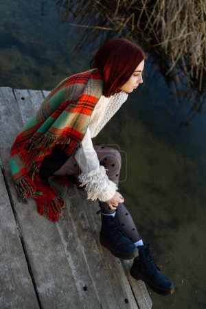 Photo for Sad teen girl sitting alone in a pier of a lake - Royalty Free Image