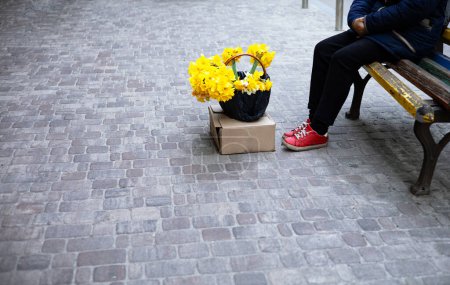 Téléchargez les photos : Vieille femme méconnaissable dans la rue vend des fleurs narcisses jaunes. - en image libre de droit