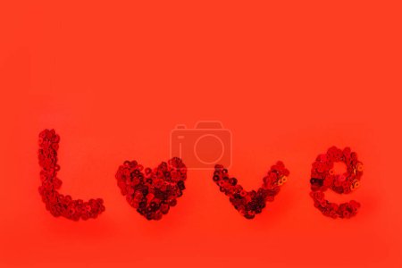Foto de La inscripción amor lentejuelas en rojo sobre un fondo de lentejuelas rojas. El concepto de sentimiento, relaciones. - Imagen libre de derechos