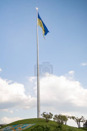 Foto de Bandera de Ucrania ondeando en el viento bajo el cielo azul, Ucrania cerca de la famosa estatua de la Madre Patria. - Imagen libre de derechos