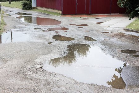 Téléchargez les photos : Cassé détruit la route délavée après une tempête de mauvais temps avec des flaques de trous en Ukraine. - en image libre de droit