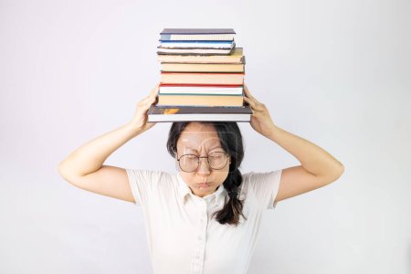 Téléchargez les photos : Jeune femme asiatique tenant une pile de livres gonflant les joues avec un visage drôle. bouche gonflée d'air, attrapant l'air. - en image libre de droit