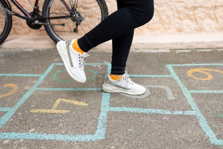 Photo for Close-up of a girl's feet and hopscotch painted on the asphalt. A child plays hopscotch on an outdoor playground on a sunny day. outdoor activities for children. - Royalty Free Image