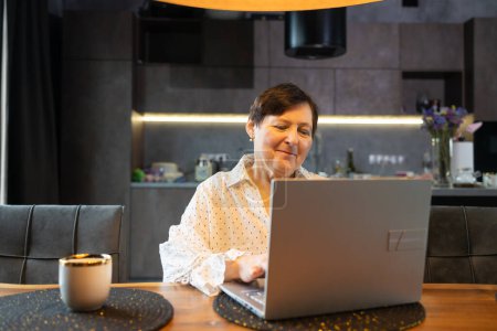 Senior mature older woman watching business training, online webinar on laptop computer remote working or social distance learning from home. 60s businesswoman video conference calling in virtual chat