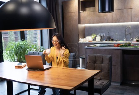 Young Asian woman having Zoom video conferencing call via computer. Home office. Stay at home and work from home concept during Coronavirus pandemic
