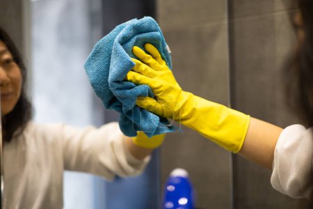 Concept de service de nettoyage. Gros plan des mains féminines dans le miroir de nettoyage des gants jaunes