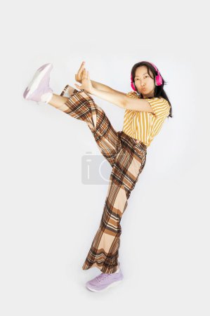 Full size body length studio portrait jump shot of glad cheerful joyful lovely Asian girl wearing trendy outfit dancing hip-hop isolated on white background.