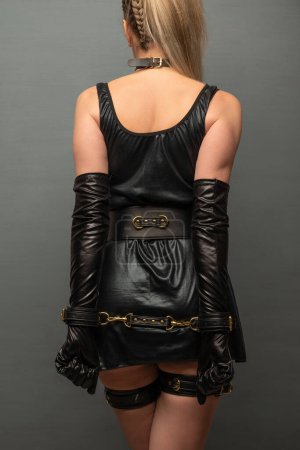 Foto de Beautiful young woman in a leather dress and bondage set posing back - Imagen libre de derechos