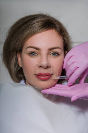 Young caucasian woman getting botox cosmetic injection in the lips. Beautiful woman gets botox injection in her face. Adult girl gets cosmetic injection of botox in a clinic. Beauty treatments. High