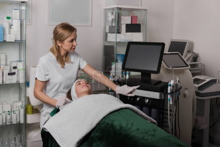 Téléchargez les photos : Femme esthéticienne utilisant une machine d'épilation laser dans un salon de beauté. Photo de haute qualité - en image libre de droit