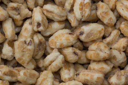 Téléchargez les photos : Dry honey puffed wheat cereal pieces scattered loosely directly above. Breakfast foods textured background, full frame image. - en image libre de droit
