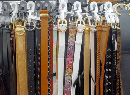 Foto de Surtido de cinturones de cuero para mujer colgando verticalmente en estantes de exhibición por sus hebillas. - Imagen libre de derechos