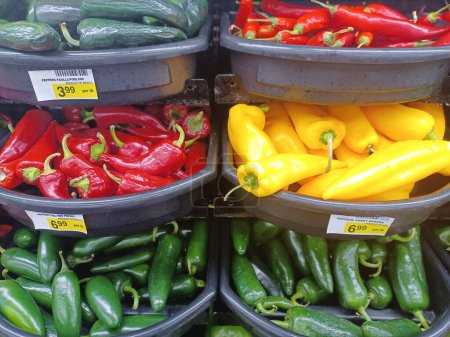 Assorted colorful hot chili peppers in a traditional vegetable market in Houston, TX closeup image. Jalapeno, Sweet banana pepper, Poblano and Red Fresno displayed.