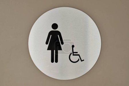 Women's bathroom and handicap sign on a wall. Circular sign and symbol designation placard.