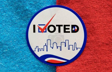 I Voted sticker split between red and blue materials indicating both Democrat and Republican party. Isolated directly above image, political concept.