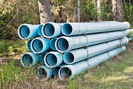 Téléchargez les photos : Paquet de tuyaux pour la construction de conduites d'eau souterraines, équipement industriel en plastique bleu pvc d'égout par secteur boisé, Houston TX USA. - en image libre de droit