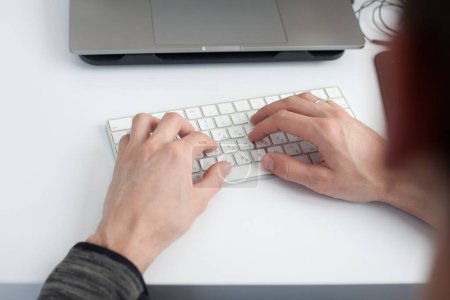 Foto de Recortado disparo de hombre escribiendo con el ordenador portátil en el lugar de trabajo en la superficie blanca para maqueta - Imagen libre de derechos