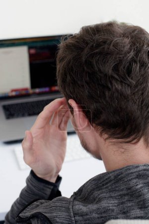 Foto de Joven estudiante masculino en la computadora pensando en resolver un problema difícil - Imagen libre de derechos