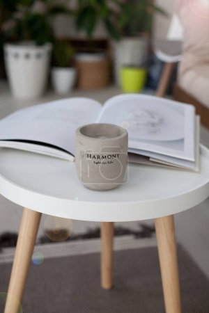 Foto de Mesa redonda blanca con una vela de hormigón de cerámica y una revista, acogedor - Imagen libre de derechos