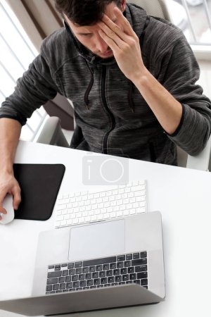 Foto de Joven estudiante masculino en la computadora pensando en resolver un problema difícil - Imagen libre de derechos